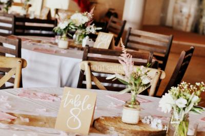 Fauteuils en rotin avec coussins blancs disposés dans un cadre naturel entouré d'arbres et de végétation.