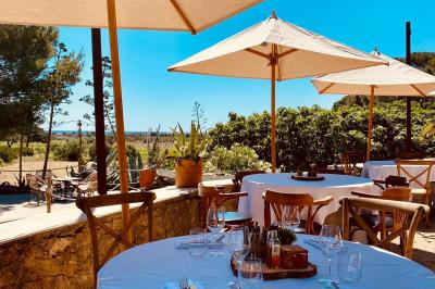 Fauteuils en rotin avec coussins blancs disposés dans un cadre naturel entouré d'arbres et de végétation.