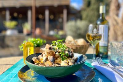 Fauteuils en rotin avec coussins blancs disposés dans un cadre naturel entouré d'arbres et de végétation.
