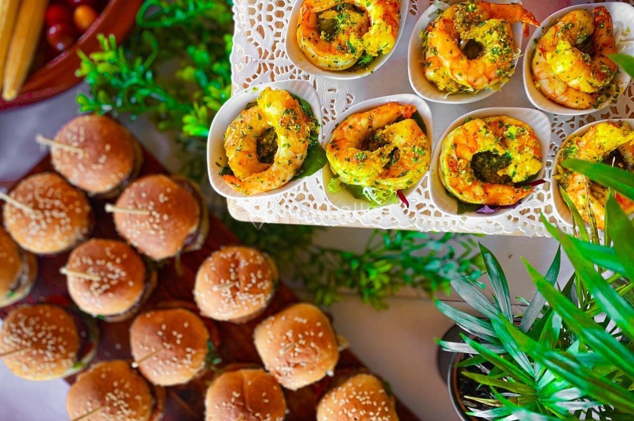 Assortiment de mini-burgers et crevettes marinées servies dans des coupelles, décorés de verdure.