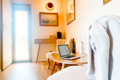 Fauteuils en rotin avec coussins blancs disposés dans un cadre naturel entouré d'arbres et de végétation.