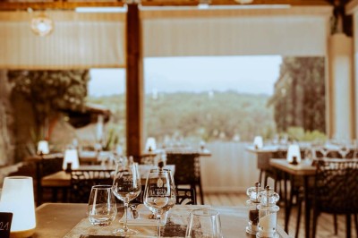 Fauteuils en rotin avec coussins blancs disposés dans un cadre naturel entouré d'arbres et de végétation.
