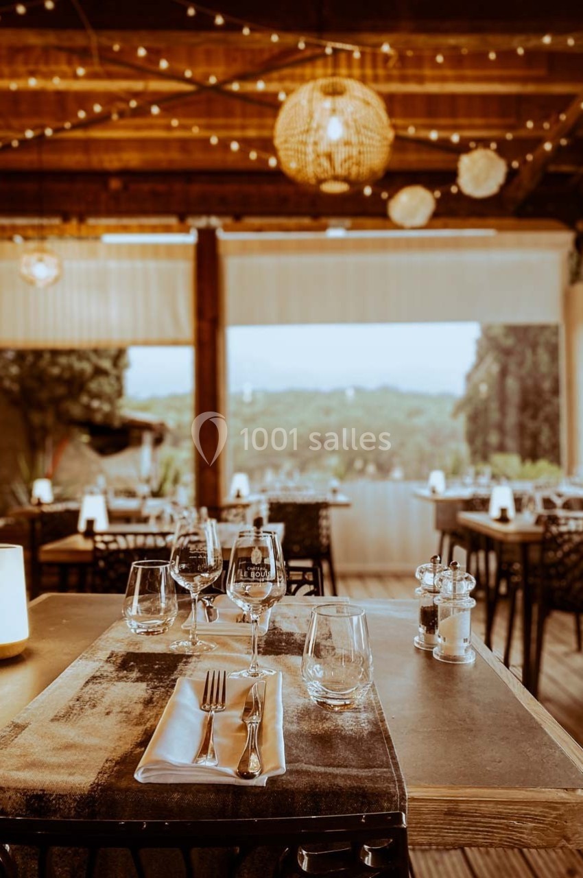 Table dressée avec couverts et verres dans un restaurant chaleureux, éclairé par des lumières suspendues.