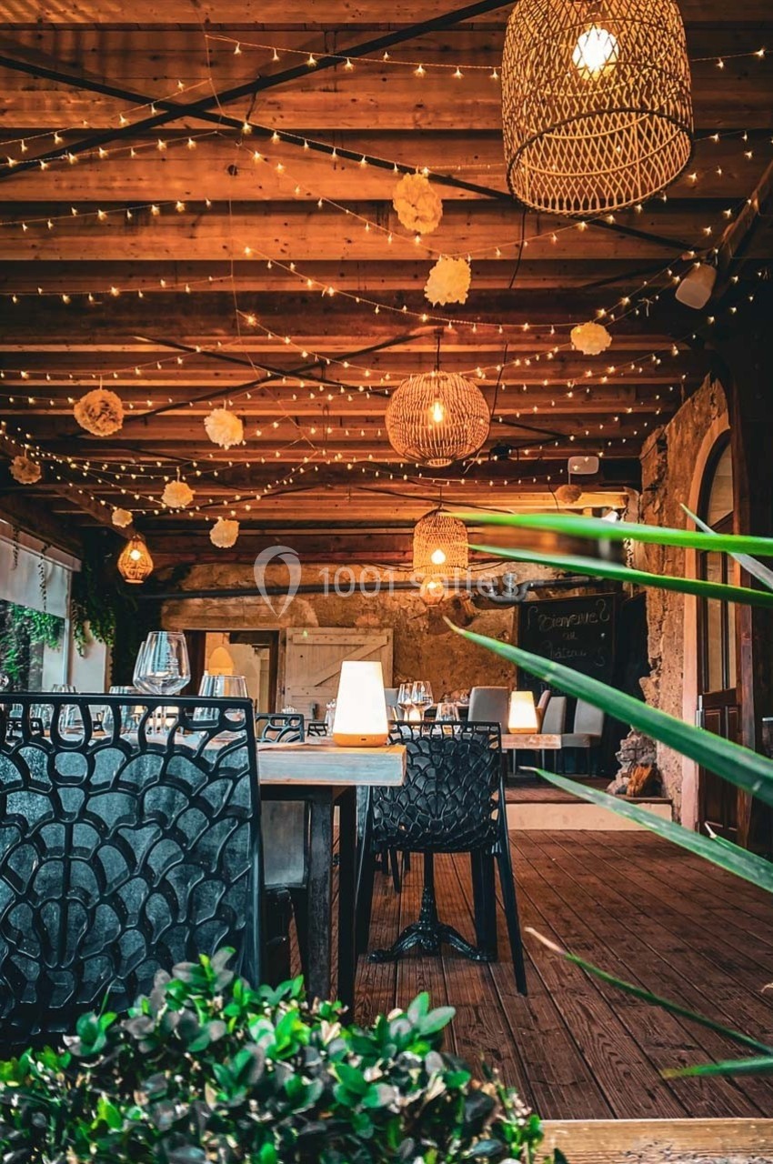 Salle à manger en bois avec éclairage chaleureux, guirlandes lumineuses et décorations suspendues.