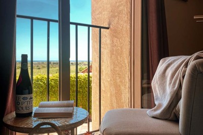 Fauteuils en rotin avec coussins blancs disposés dans un cadre naturel entouré d'arbres et de végétation.