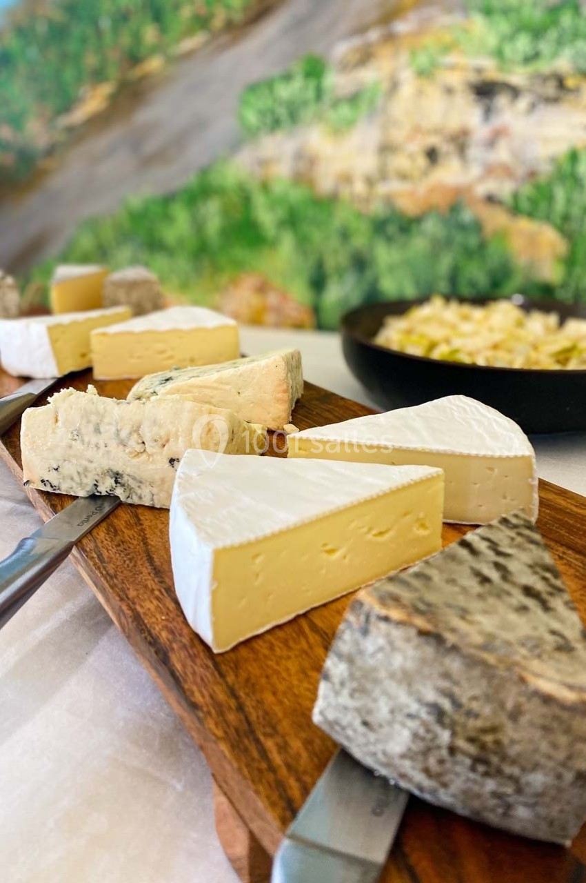 Plateau en bois avec divers fromages, dont des fromages à pâte molle et à croûte fleurie, présenté sur une table.