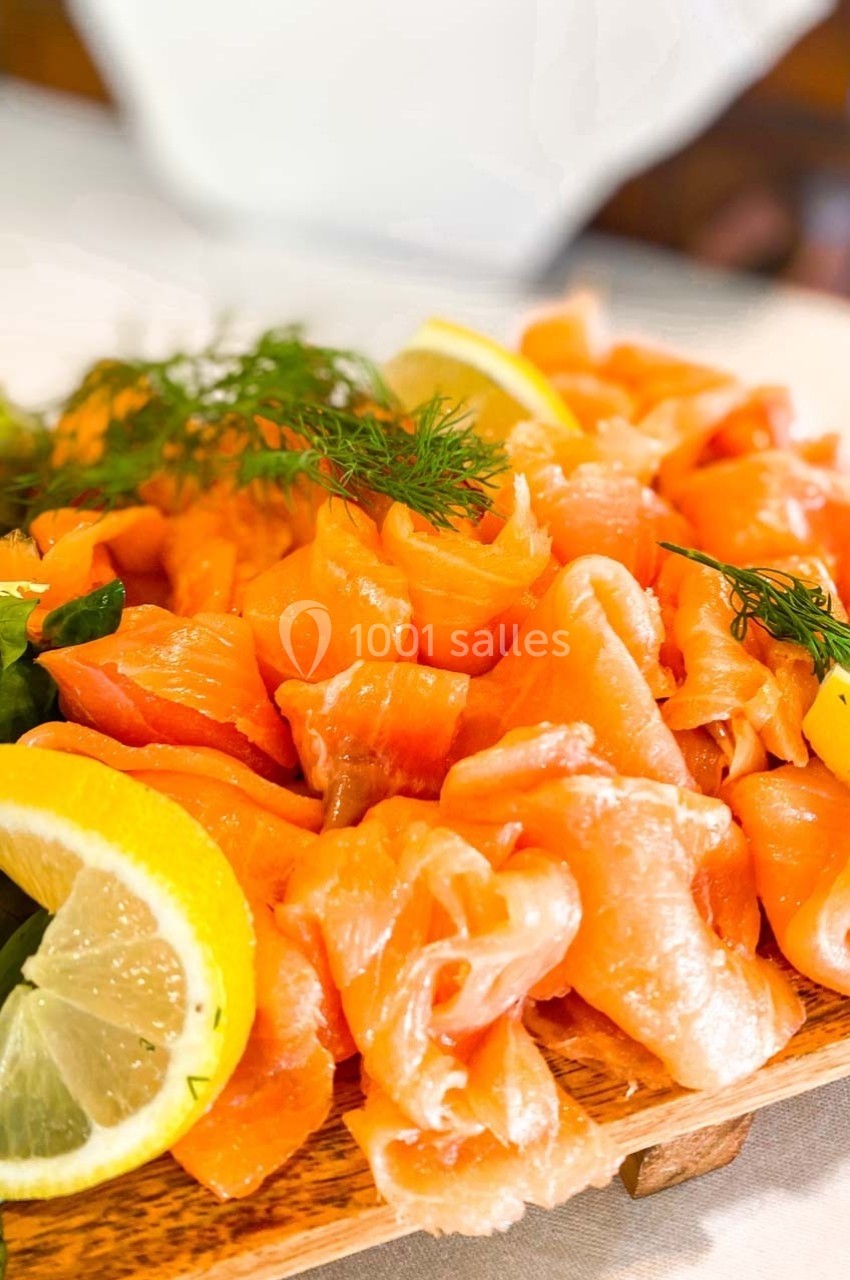 Tranches de saumon fumé garnies de citron, d'aneth et de salade verte sur une planche en bois.