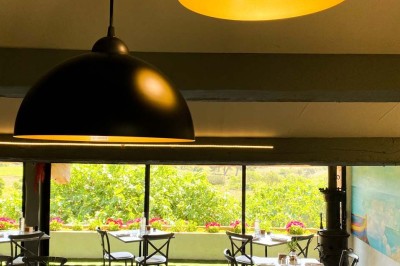 Fauteuils en rotin avec coussins blancs disposés dans un cadre naturel entouré d'arbres et de végétation.