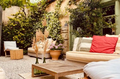 Fauteuils en rotin avec coussins blancs disposés dans un cadre naturel entouré d'arbres et de végétation.