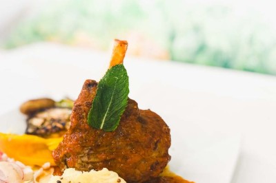 Fauteuils en rotin avec coussins blancs disposés dans un cadre naturel entouré d'arbres et de végétation.