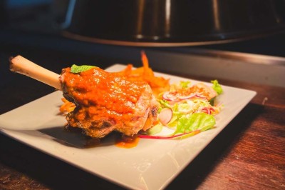 Fauteuils en rotin avec coussins blancs disposés dans un cadre naturel entouré d'arbres et de végétation.