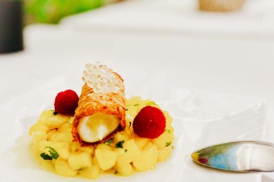 Fauteuils en rotin avec coussins blancs disposés dans un cadre naturel entouré d'arbres et de végétation.