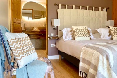 Fauteuils en rotin avec coussins blancs disposés dans un cadre naturel entouré d'arbres et de végétation.