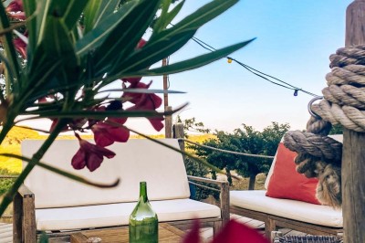 Fauteuils en rotin avec coussins blancs disposés dans un cadre naturel entouré d'arbres et de végétation.