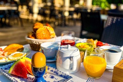Fauteuils en rotin avec coussins blancs disposés dans un cadre naturel entouré d'arbres et de végétation.