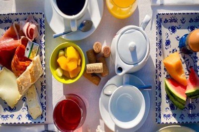 Fauteuils en rotin avec coussins blancs disposés dans un cadre naturel entouré d'arbres et de végétation.