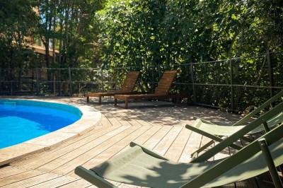 Fauteuils en rotin avec coussins blancs disposés dans un cadre naturel entouré d'arbres et de végétation.
