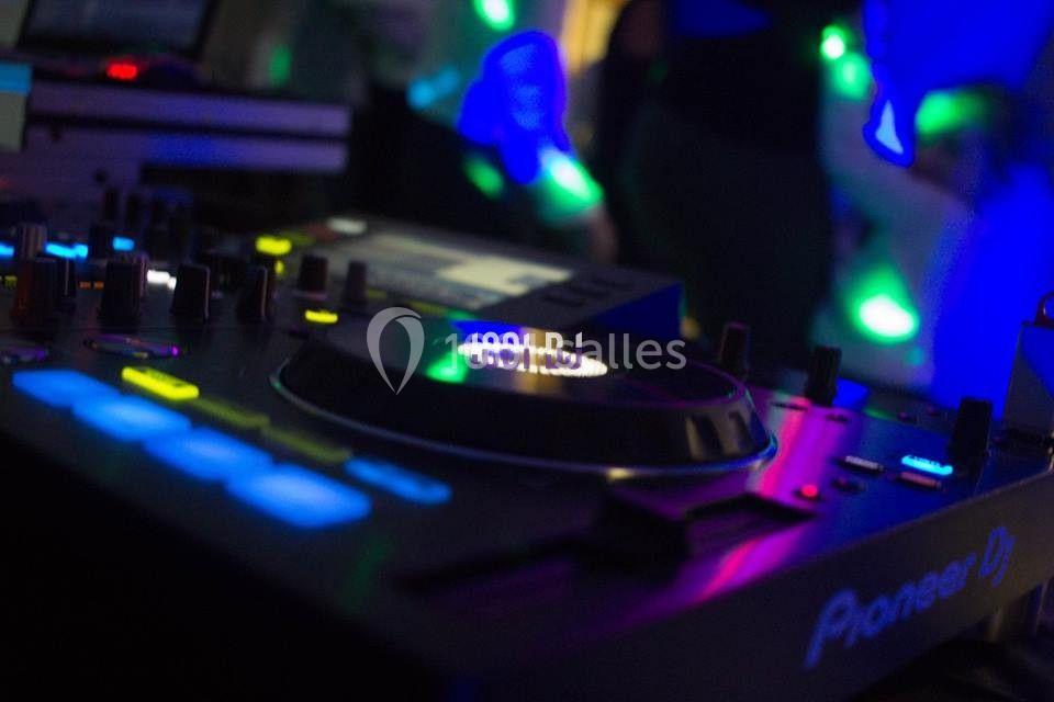 Table de mixage éclairée par des lumières colorées dans une ambiance de soirée.