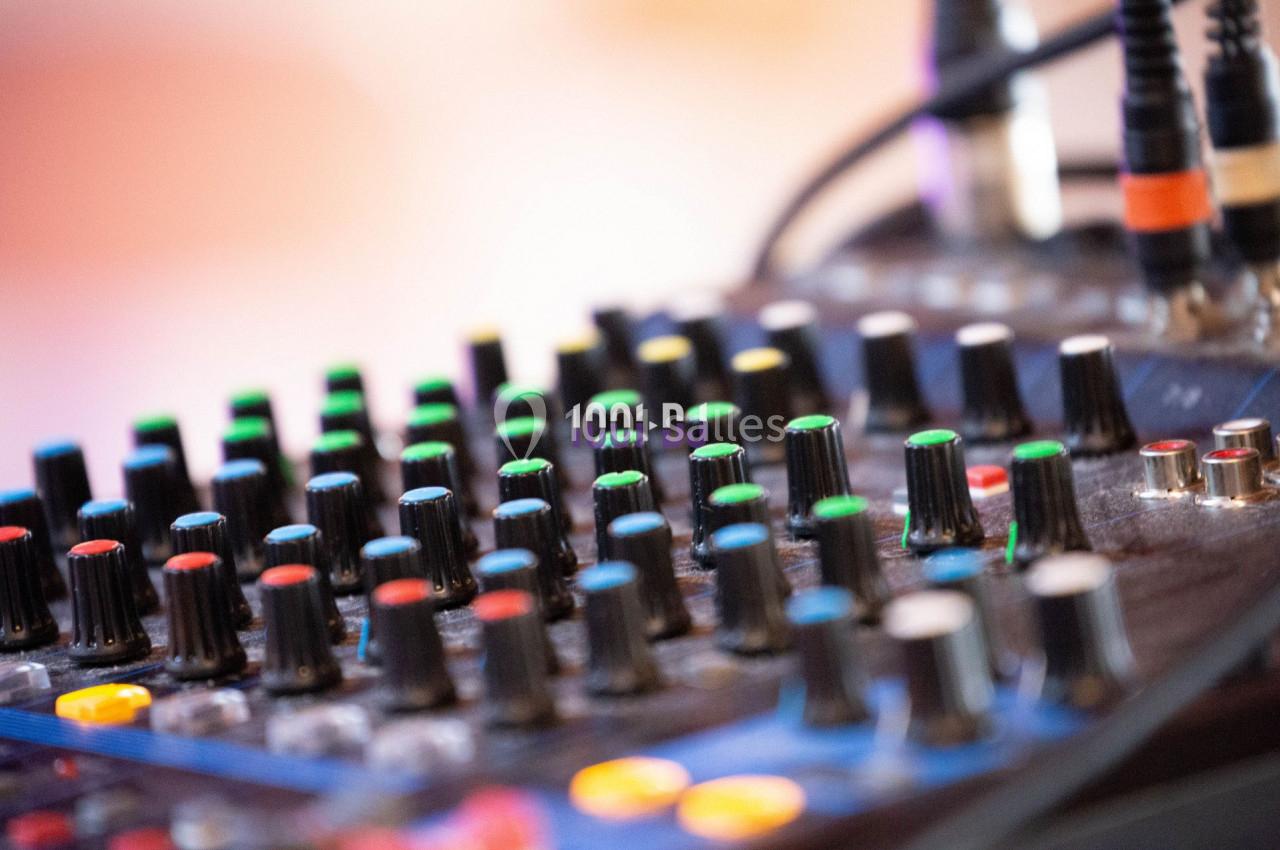 Table de mixage audio avec de nombreux boutons et curseurs colorés, utilisée pour régler le son.