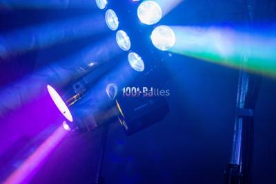 Structure en bois d'une halle éclairée par des lumières violettes, avec un toit en tuiles et des piliers en pierre.