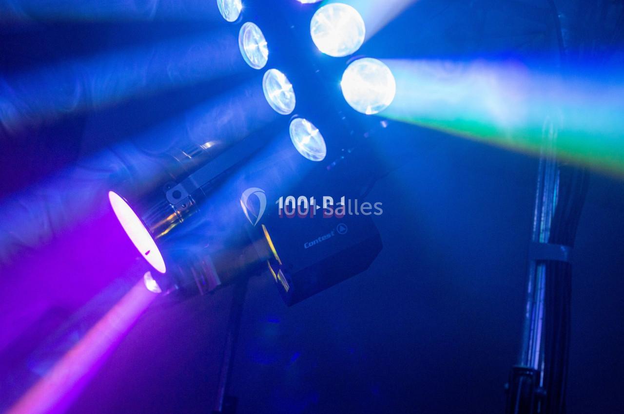 Projecteur lumineux émettant des faisceaux colorés dans une ambiance sombre.