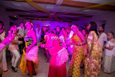 Structure en bois d'une halle éclairée par des lumières violettes, avec un toit en tuiles et des piliers en pierre.