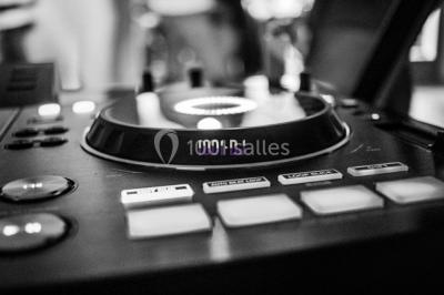 Salle voûtée avec colonnes en pierre, décorée de guirlandes végétales et éclairée par des lumières rouges et un DJ en…