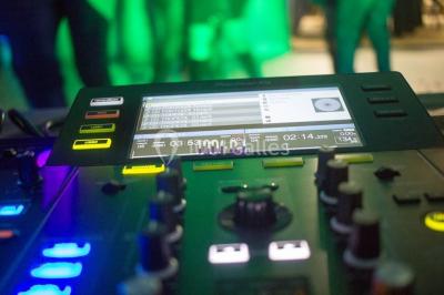 Salle voûtée avec colonnes en pierre, décorée de guirlandes végétales et éclairée par des lumières rouges et un DJ en…