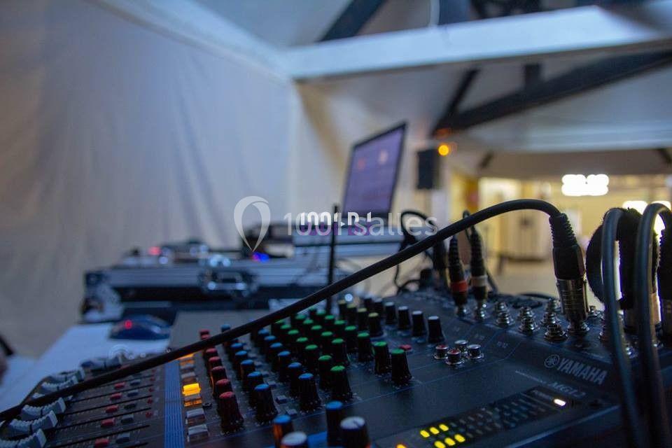 Table de mixage avec câbles connectés, entourée d'équipements audio et d'un écran d'ordinateur en arrière-plan.