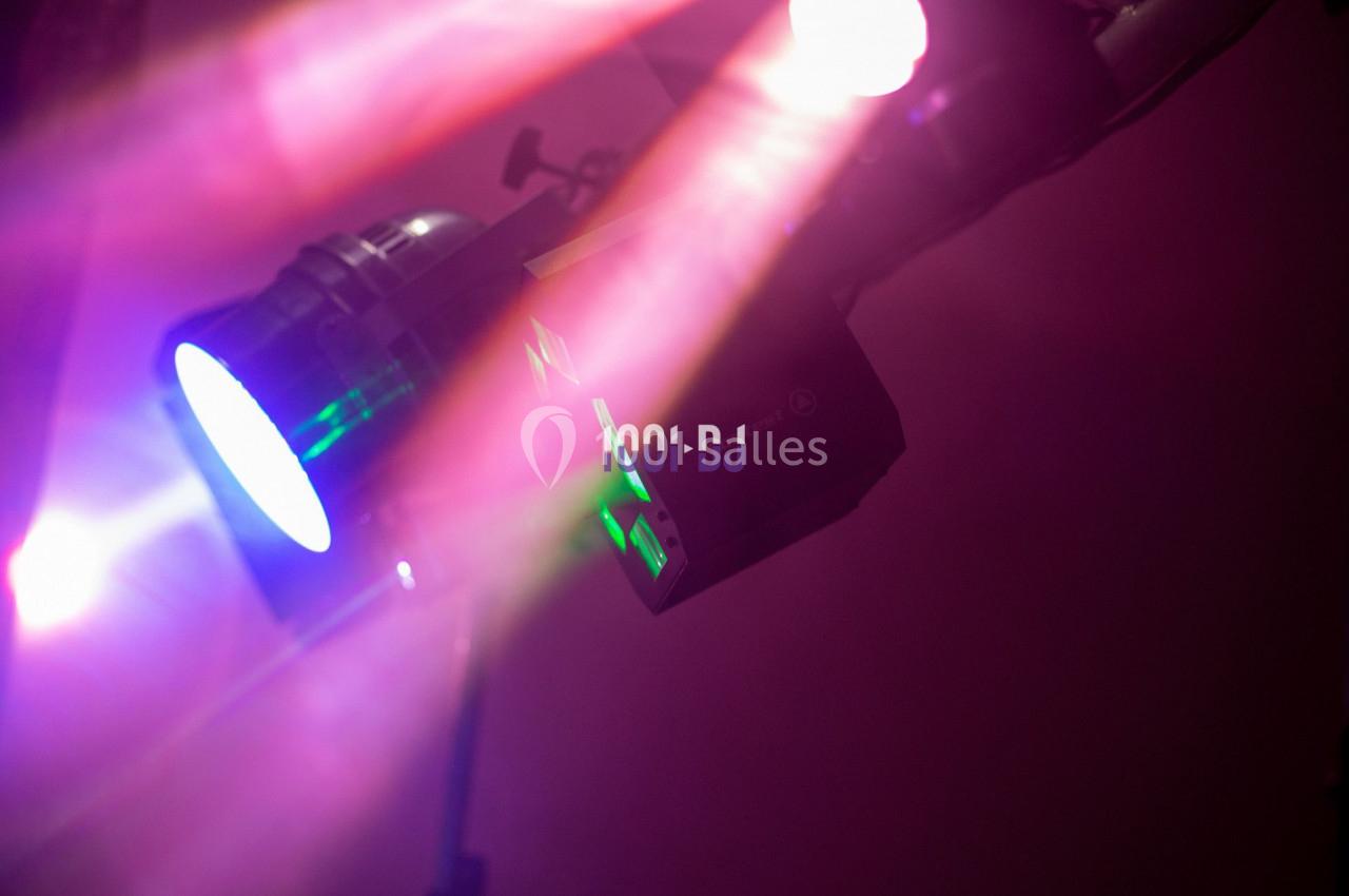 Projecteurs colorés diffusant des faisceaux lumineux roses et verts dans une ambiance sombre.