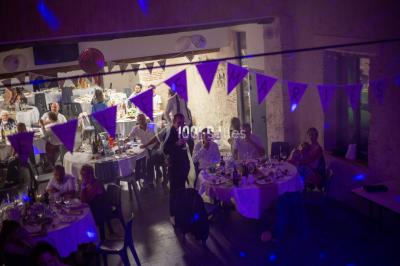 Salle voûtée avec colonnes en pierre, décorée de guirlandes végétales et éclairée par des lumières rouges et un DJ en…