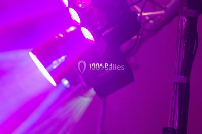 Salle voûtée avec colonnes en pierre, décorée de guirlandes végétales et éclairée par des lumières rouges et un DJ en…