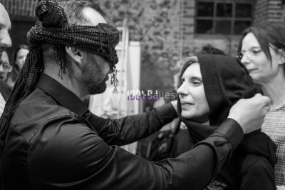 Salle voûtée avec colonnes en pierre, décorée de guirlandes végétales et éclairée par des lumières rouges et un DJ en…