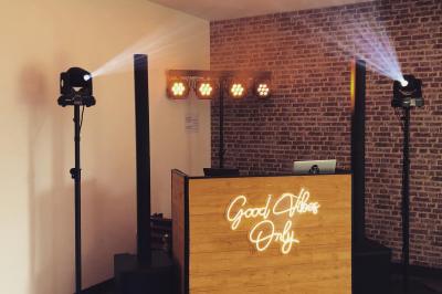 Salle voûtée avec colonnes en pierre, décorée de guirlandes végétales et éclairée par des lumières rouges et un DJ en…