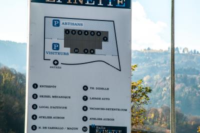 Panneau indiquant les services et parkings du bâtiment Épinette, avec un lampadaire et un paysage en arrière-plan.
