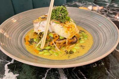 Assiette avec un bloc de foie gras, tranche de pain brioché, poire pochée et décorations de crème et noisettes.