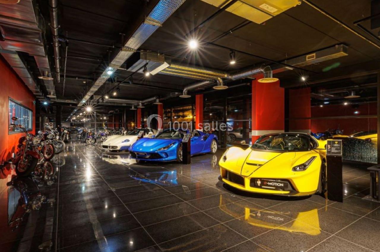 Salle d'exposition avec des voitures de sport colorées et des motos alignées sur un sol brillant sous un éclairage…