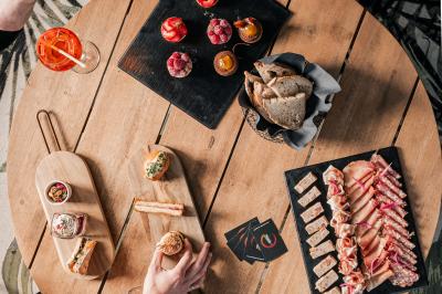 Vue de dessus d'une table en bois avec des planches apéritives, tapas variés et boissons colorées.