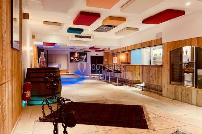 Salle aménagée avec une longue table dressée pour un repas, entourée de chaises pliantes et décorée sobrement.