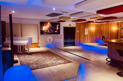 Salle aménagée avec une longue table dressée pour un repas, entourée de chaises pliantes et décorée sobrement.