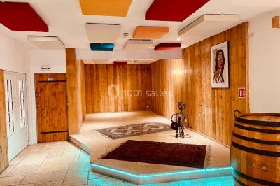 Salle aménagée avec une longue table dressée pour un repas, entourée de chaises pliantes et décorée sobrement.