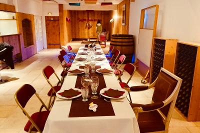 Salle aménagée avec une longue table dressée pour un repas, entourée de chaises pliantes et décorée sobrement.