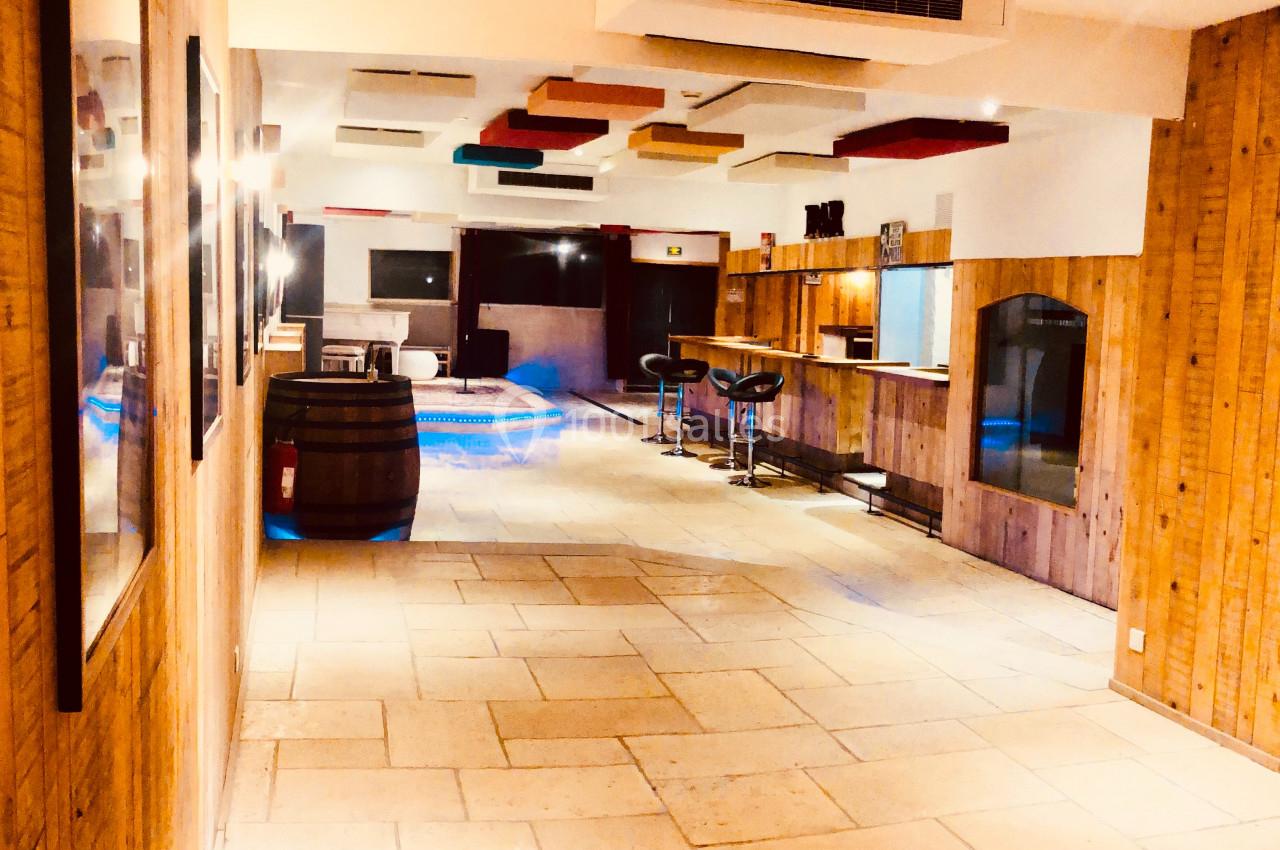 Couloir lumineux avec murs en bois, bar avec tabourets à droite et plafond décoré de panneaux colorés.