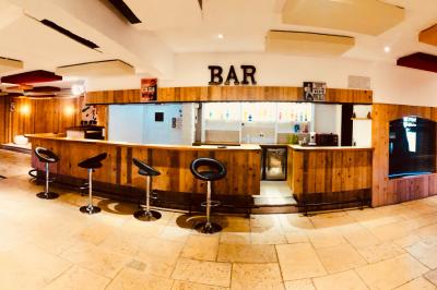 Salle aménagée avec une longue table dressée pour un repas, entourée de chaises pliantes et décorée sobrement.