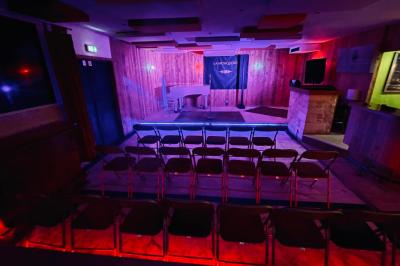 Salle aménagée avec une longue table dressée pour un repas, entourée de chaises pliantes et décorée sobrement.