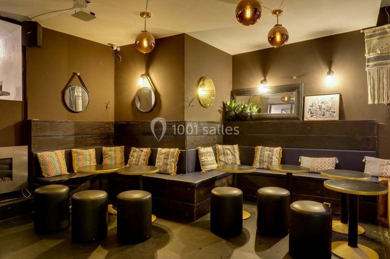 Espace intérieur chaleureux avec banquettes, coussins colorés, tables basses et luminaires suspendus en cuivre.