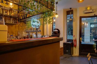 Salon cosy avec tables rondes, tabourets noirs, coussins décoratifs et éclairage tamisé près de grandes fenêtres.