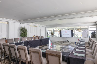 Table dressée pour un petit-déjeuner en extérieur avec vue sur la mer, sous un ciel bleu parsemé de nuages.
