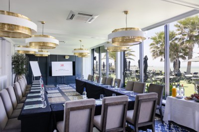 Table dressée pour un petit-déjeuner en extérieur avec vue sur la mer, sous un ciel bleu parsemé de nuages.