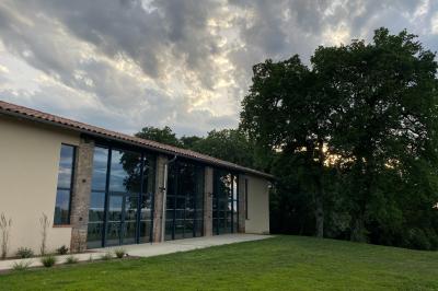 Un couple dans une voiture ancienne quitte un bâtiment entouré de verdure par une journée ensoleillée.